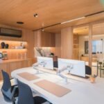 Modern ergonomic home office workstation with dual monitor setup wooden accents and task lighting