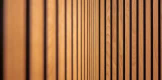 Acoustic Wall Paneling and Noise Reduction Solutions for Remote Workspaces Modern acoustic wood slat wall paneling installed in a home office workspace for sound absorption