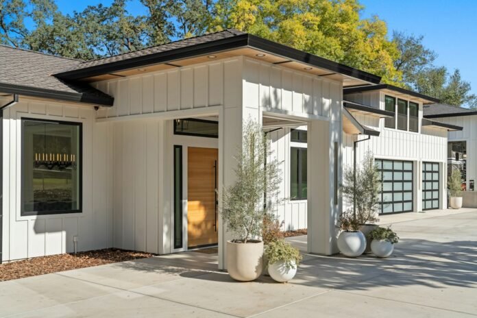 Contemporary modern farmhouse exterior featuring crisp white vertical board and batten siding high contrast black window frames and warm natural wood accents